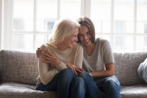 Mother and daughter sitting on a couch smiling and hugging
